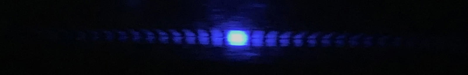 Pola difraksi celah tunggal dari laser biru pada karton putih, 12 Januari 2026. Dokumentasi kualitatif, bukan data pengukuran redaksi; berkas diubah ukuran dan dikonversi ke JPEG.