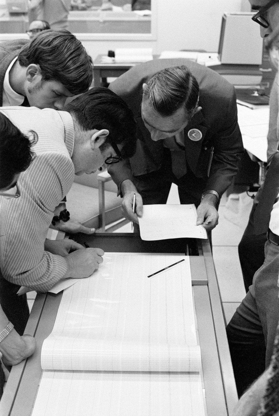 Ilmuwan mempelajari rekaman seismometer setelah tumbukan tingkat roket Apollo 15, Mission Control Center, 29 Juli 1971. Arsip NASA/JSC S71-41422; fotografer individual tidak dicantumkan. Bukan foto instrumen PRISM 2026 atau pangkalan Bulan.