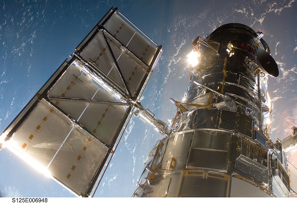 Teleskop Antariksa Hubble setelah ditangkap lengan robot wahana Atlantis, 13 Mei 2009. Foto arsip instrumen; bukan citra NGC 1827 yang dibahas.