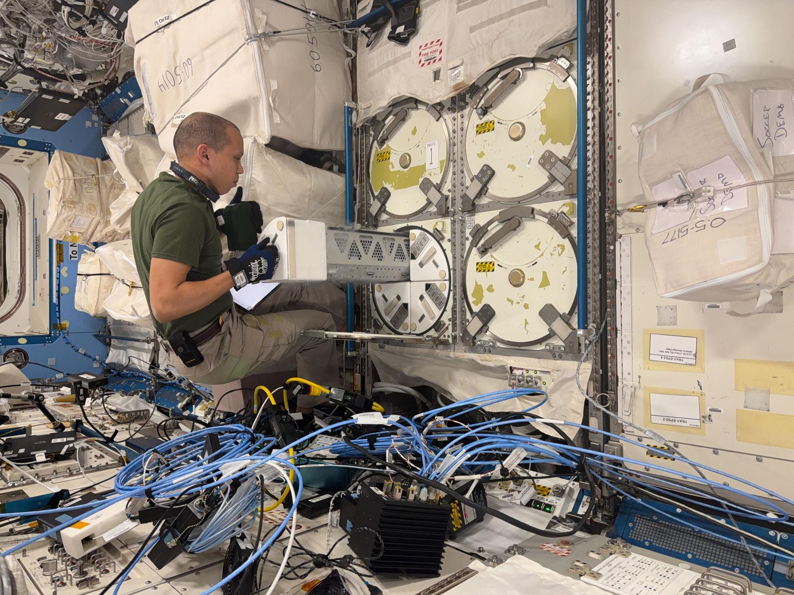 Chris Williams memasukkan wadah kriogenik ke freezer riset di modul Kibo, 12 Mei 2026. Foto NASA/Chris Williams, nomor iss074e0590846; dokumentasi penyimpanan sampel, bukan pembongkaran kargo pada Oktober 2026.